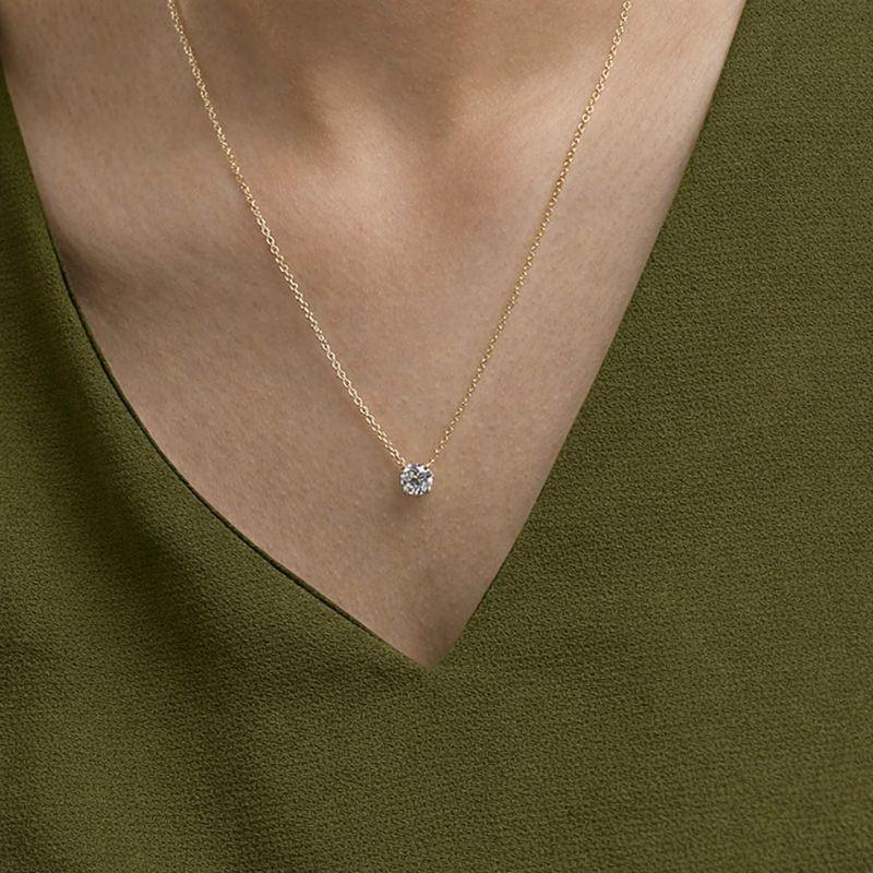 Woman wearing a gold chain necklace with a round lab grown diamond pendant from Delux Jewelry.