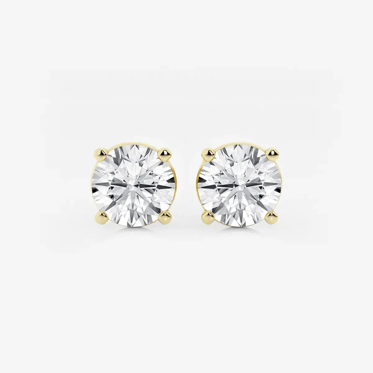 Round lab grown diamond stud earrings with yellow gold prong settings on white background