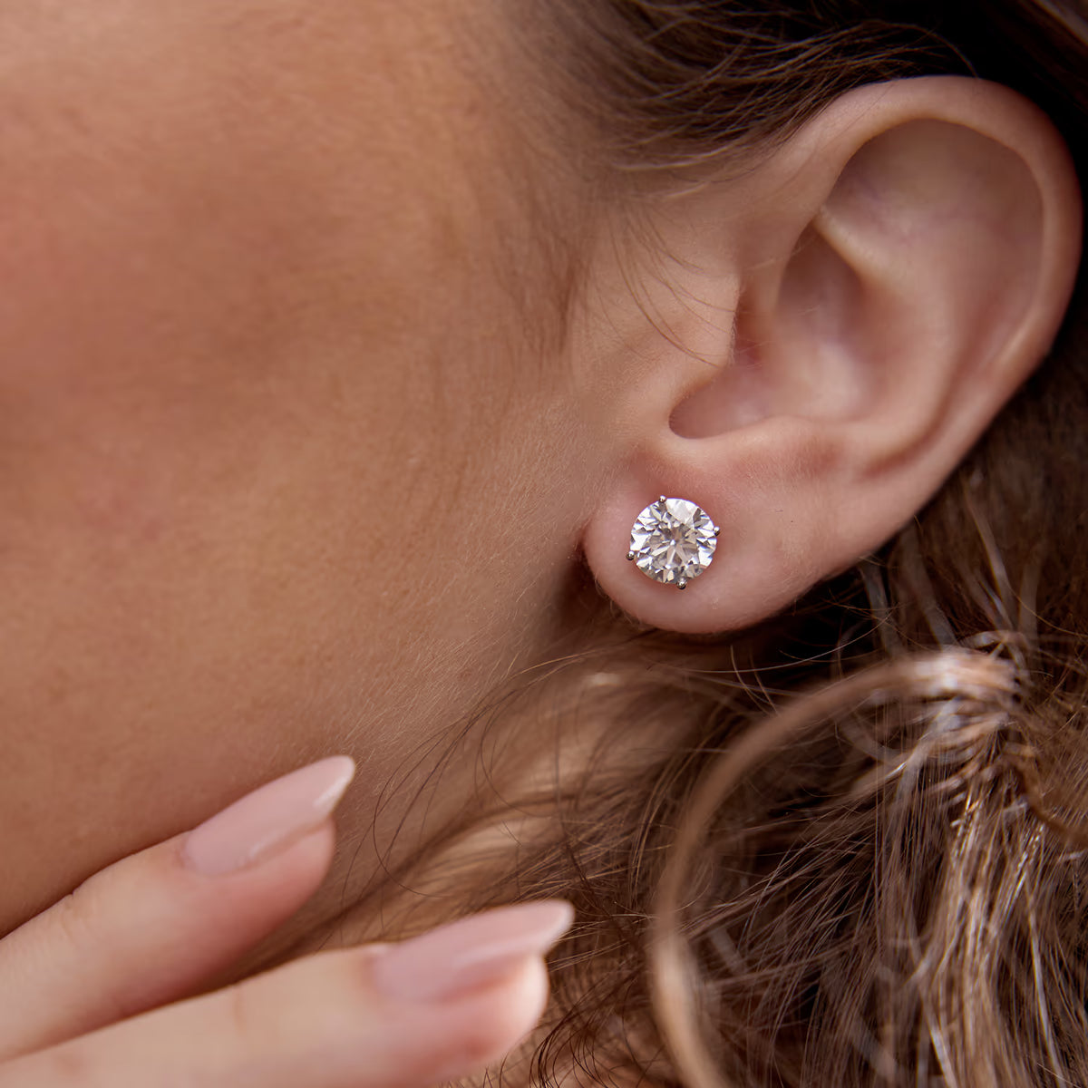 Close-up of round lab grown diamond stud earring from Delux Jewelry on woman's ear
